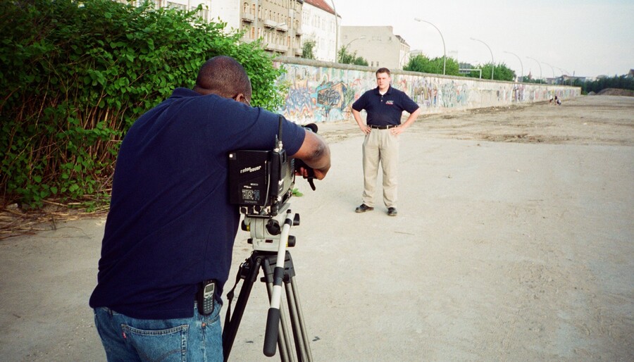 A cameraman filming Kane Farabaugh at the Berlin Wall
