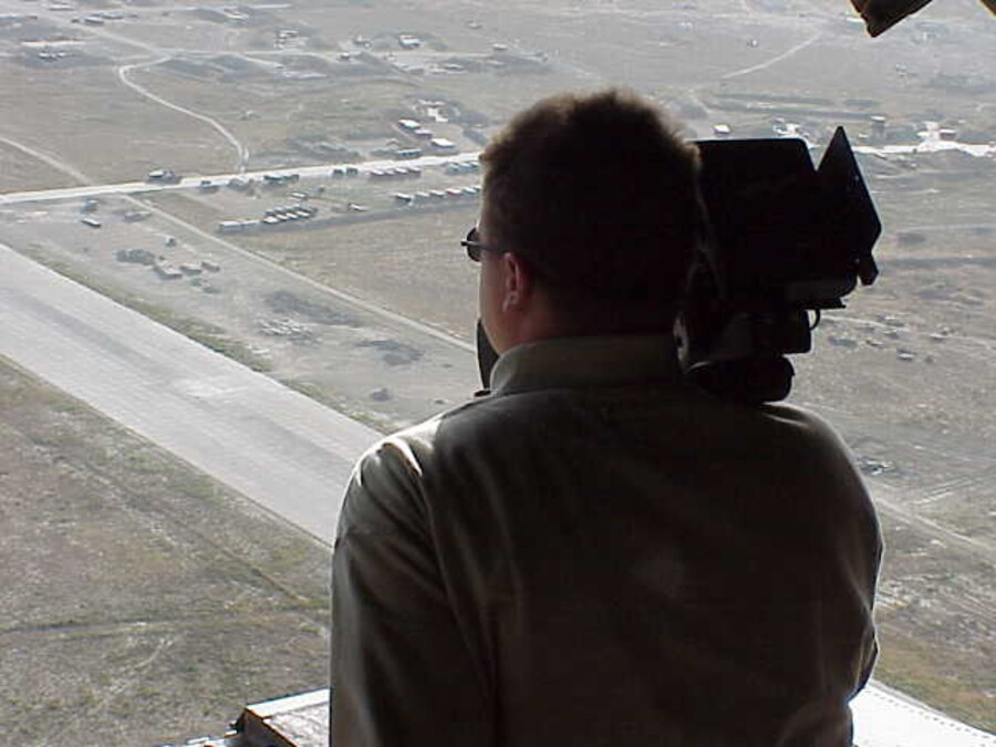 A cameraman filming aerial footage from an aircraft